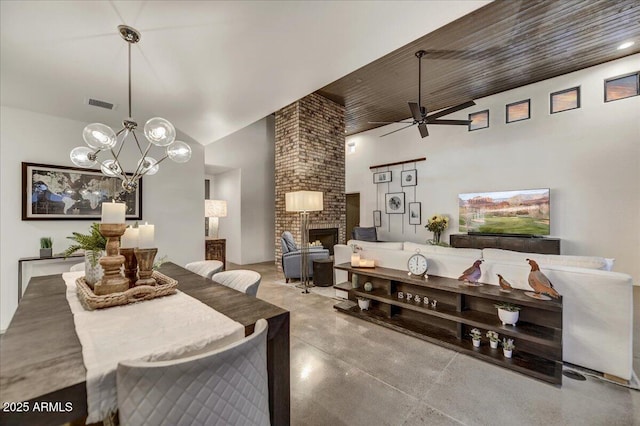 dining room with visible vents, a ceiling fan, finished concrete floors, a fireplace, and lofted ceiling