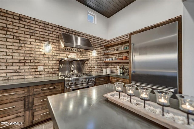 kitchen with open shelves, premium appliances, dark countertops, and wall chimney exhaust hood