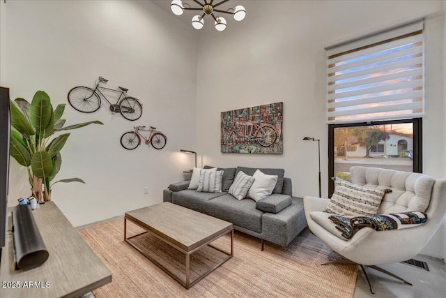 living area with visible vents, a notable chandelier, and a towering ceiling