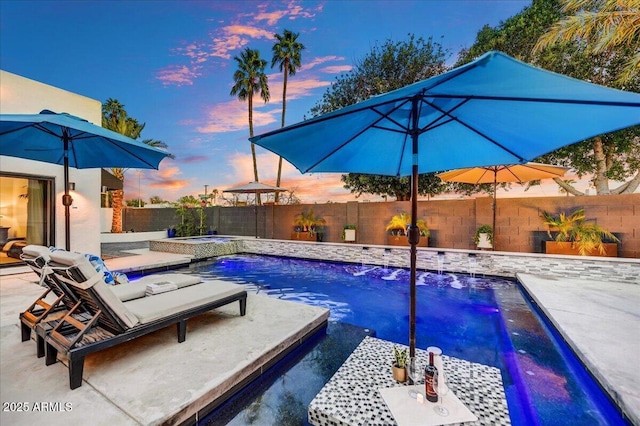 pool at dusk featuring a patio area, a fenced in pool, an in ground hot tub, and a fenced backyard