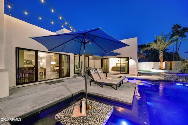 pool at night with a fenced in pool, a patio, an in ground hot tub, and fence