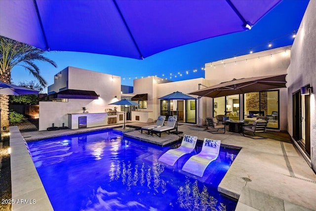 outdoor pool with exterior kitchen and a patio area