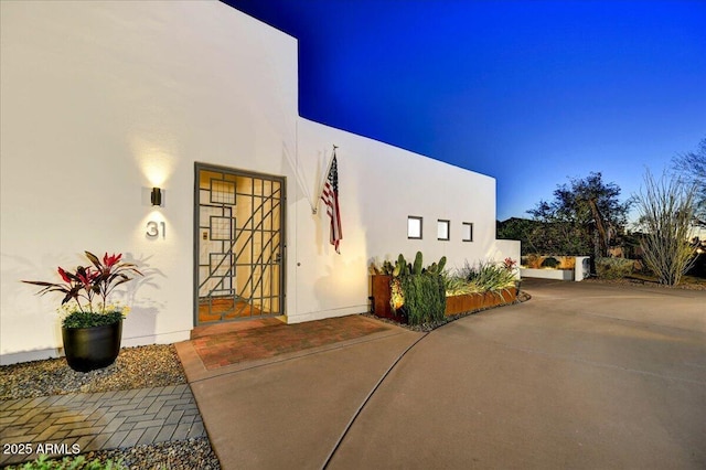 entrance to property featuring a patio area, stucco siding, and fence