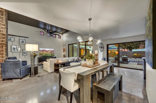 dining area with ceiling fan with notable chandelier, finished concrete flooring, and a towering ceiling