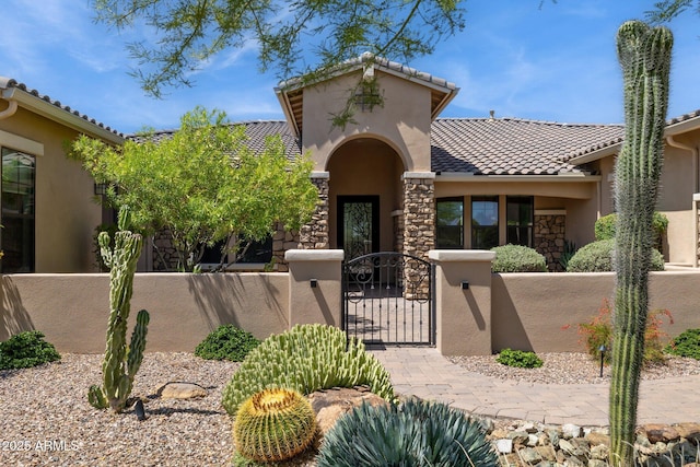 6450 E Monterra Way, Scottsdale, AZ 85266 - mediterranean / spanish house featuring a fenced front yard, stucco siding, a gate, a tiled roof, and stone siding