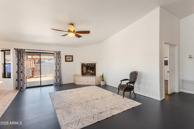 living room featuring a tiled fireplace, visible vents, baseboards, and ceiling fan