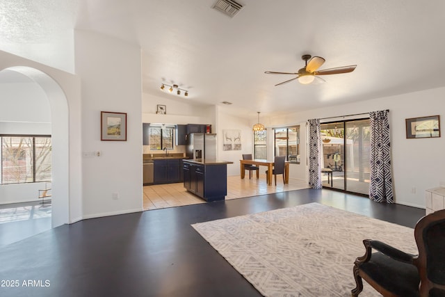 interior space featuring arched walkways, ceiling fan, visible vents, and a wealth of natural light