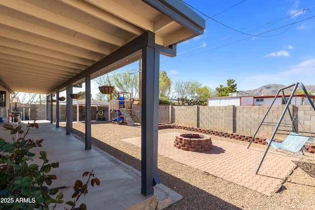 view of patio / terrace with a fenced backyard, an outdoor fire pit, and a playground