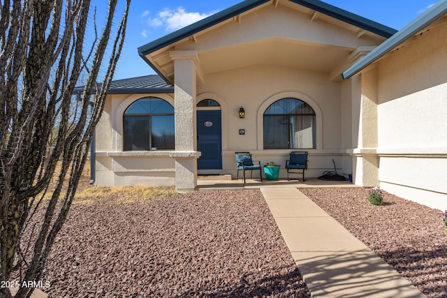 doorway to property with a porch and stucco siding