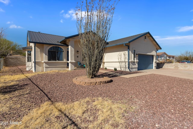 ranch-style home with metal roof, stucco siding, and driveway