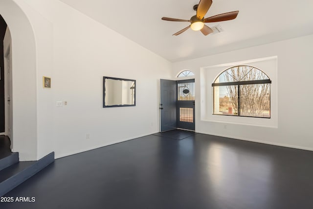 foyer entrance with visible vents, arched walkways, a ceiling fan, vaulted ceiling, and finished concrete floors