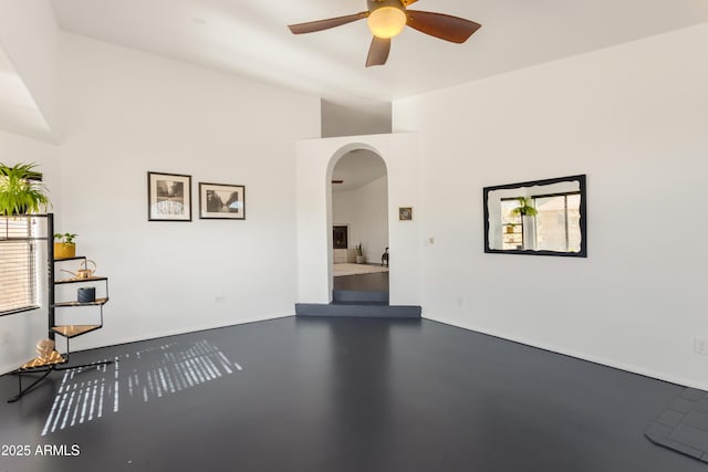 unfurnished room featuring a wealth of natural light, arched walkways, and a ceiling fan