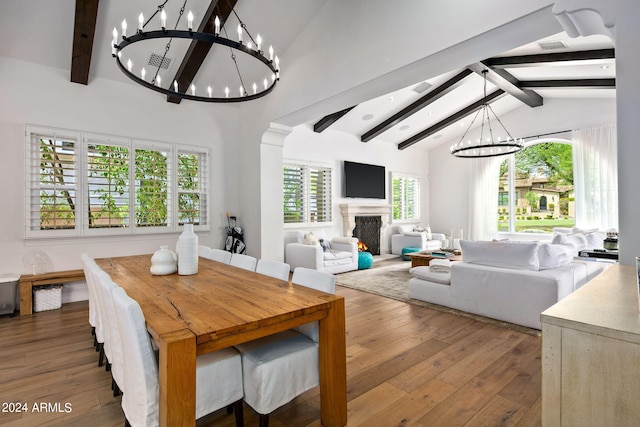 dining room featuring lofted ceiling with beams, an inviting chandelier, a premium fireplace, and wood finished floors