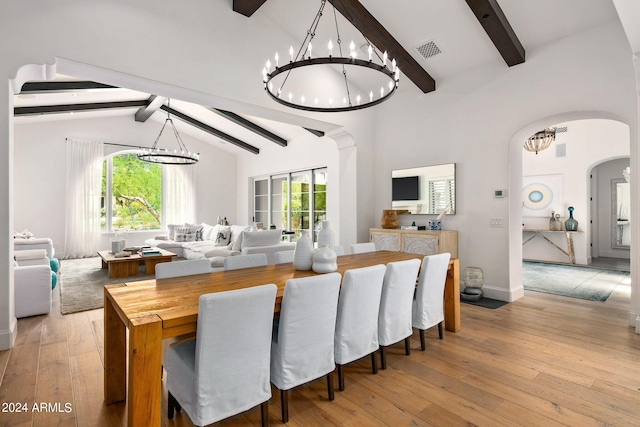 dining space with light wood-type flooring, arched walkways, a chandelier, and visible vents