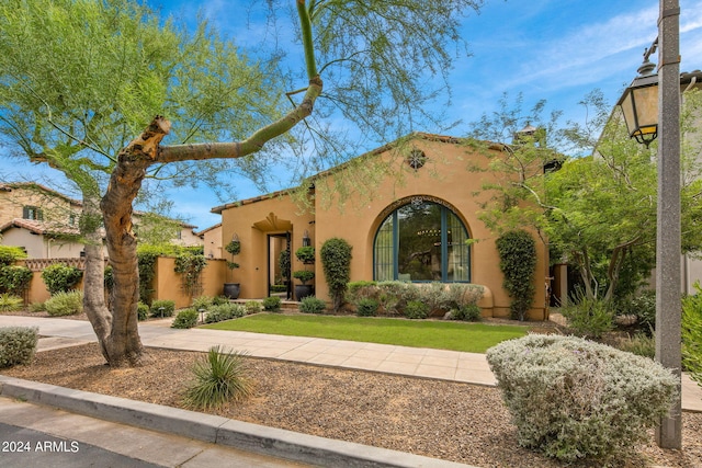 mediterranean / spanish-style house with fence, a front lawn, and stucco siding