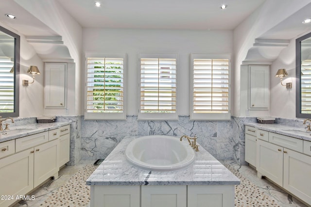 bathroom featuring a wainscoted wall, a sink, tile walls, and a garden tub