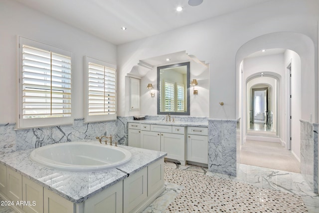 bathroom with a garden tub, recessed lighting, a wainscoted wall, tile walls, and vanity