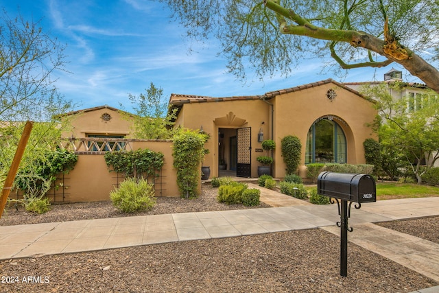 mediterranean / spanish-style house featuring fence, a tile roof, and stucco siding