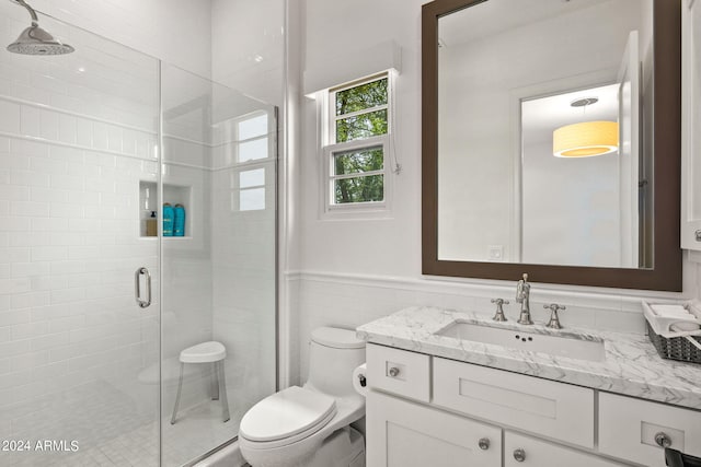 full bath featuring a wainscoted wall, tile walls, toilet, a stall shower, and vanity