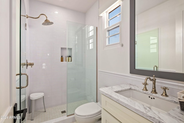 bathroom featuring toilet, wainscoting, a shower stall, and vanity