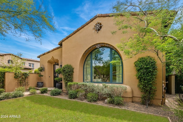 view of front of home featuring a front lawn, a tile roof, and stucco siding