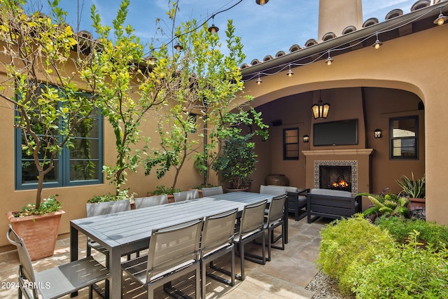 view of patio with outdoor dining space and a lit fireplace