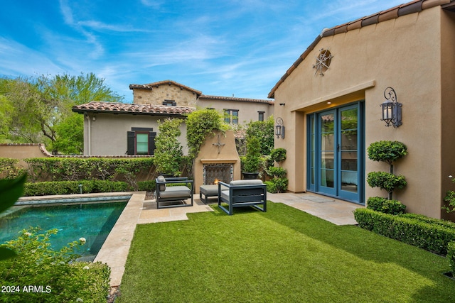 back of house with a warm lit fireplace, a patio, fence, a tile roof, and stucco siding