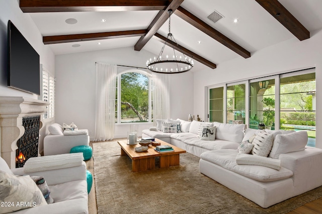 living room featuring lofted ceiling with beams, a premium fireplace, visible vents, and a notable chandelier