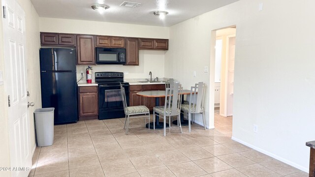 kitchen featuring light tile patterned flooring, a sink, visible vents, light countertops, and black appliances