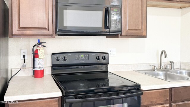 kitchen featuring black appliances, light countertops, and a sink