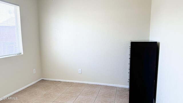 empty room featuring baseboards and light tile patterned floors