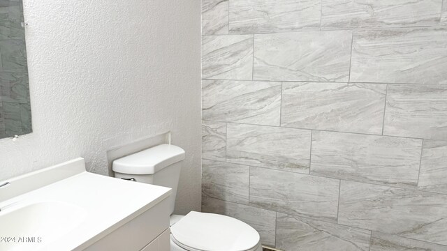 bathroom featuring toilet, vanity, and a textured wall