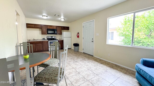 kitchen featuring black microwave, visible vents, electric stove, light countertops, and freestanding refrigerator