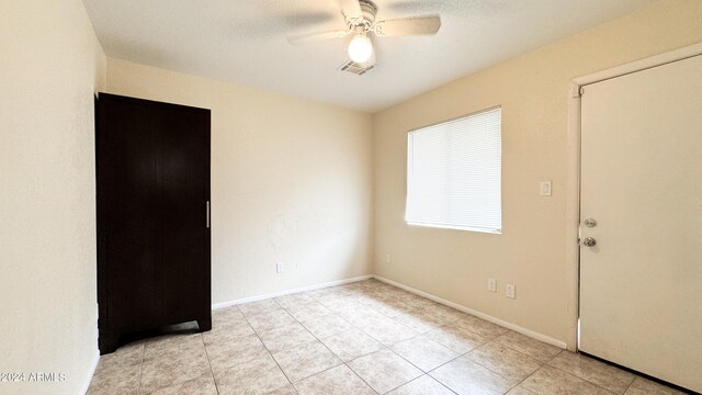 empty room with baseboards, visible vents, a ceiling fan, and light tile patterned flooring