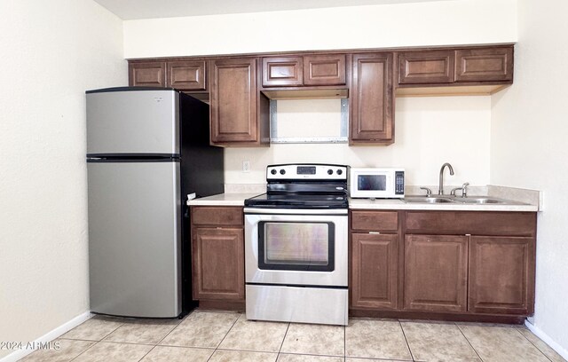 kitchen with light tile patterned flooring, stainless steel appliances, a sink, and light countertops