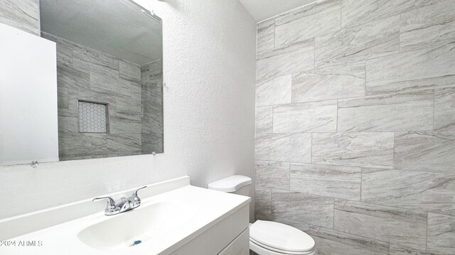 bathroom with a textured wall, vanity, and toilet