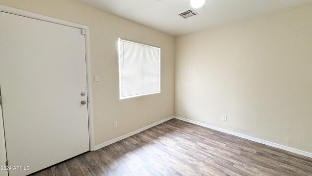 empty room with baseboards, visible vents, and wood finished floors