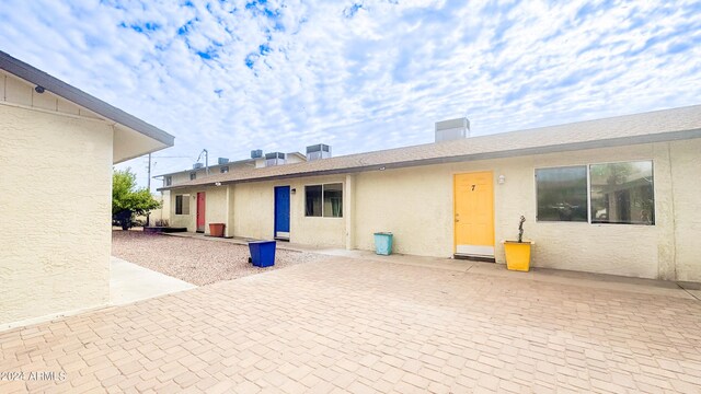 rear view of house with central AC unit, a patio, and stucco siding