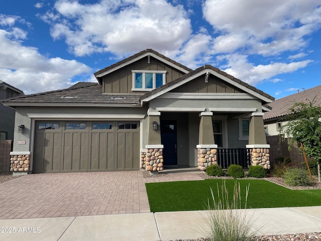 craftsman inspired home with a porch, a garage, stone siding, decorative driveway, and board and batten siding