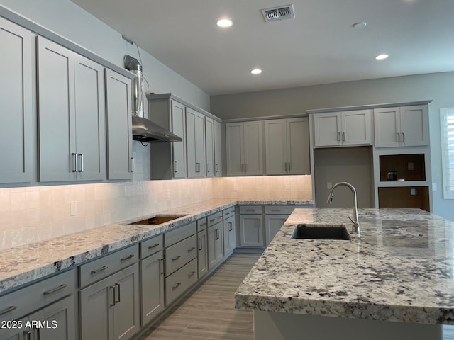 kitchen with visible vents, gray cabinetry, an island with sink, a sink, and black electric cooktop