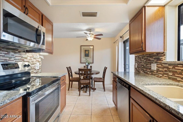 16510 E Palisades Blvd Unit 42, Fountain Hills, AZ 85268 - kitchen with appliances with stainless steel finishes, decorative backsplash, brown cabinets, and light stone countertops
