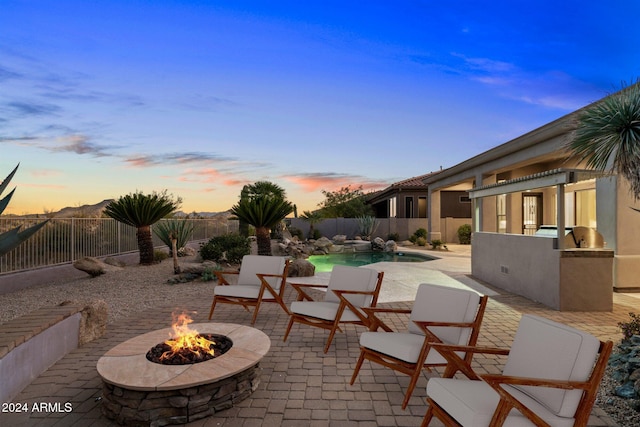 34599 N 99th Way, Scottsdale, AZ 85262 - patio terrace at dusk with an outdoor fire pit, a fenced backyard, a patio, and an outdoor kitchen