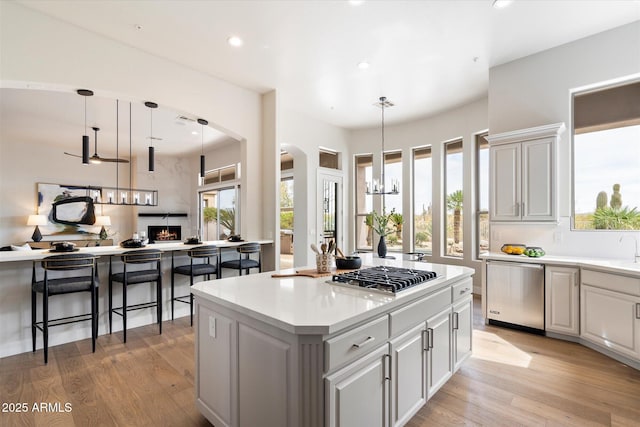 34599 N 99th Way, Scottsdale, AZ 85262 - kitchen with stainless steel appliances, a kitchen island, arched walkways, a chandelier, and light wood-style flooring