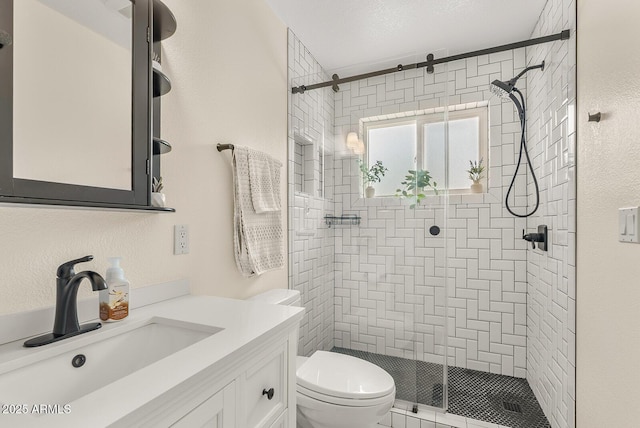 full bathroom featuring a stall shower, a textured wall, toilet, a textured ceiling, and vanity