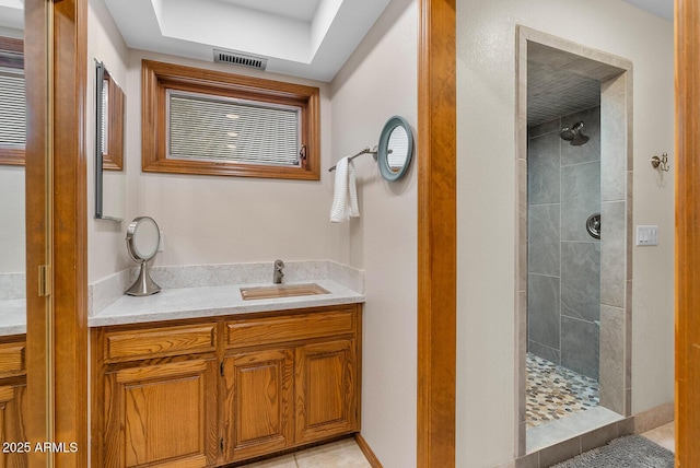 full bathroom with visible vents, a sink, and a tile shower