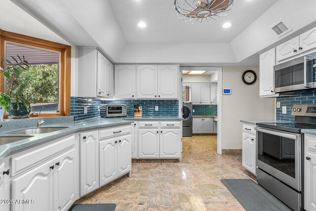 kitchen featuring stainless steel appliances, washer / clothes dryer, visible vents, backsplash, and white cabinets