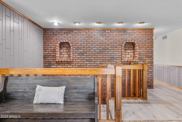 room details featuring a wainscoted wall, visible vents, ornamental molding, a textured ceiling, and wood finished floors