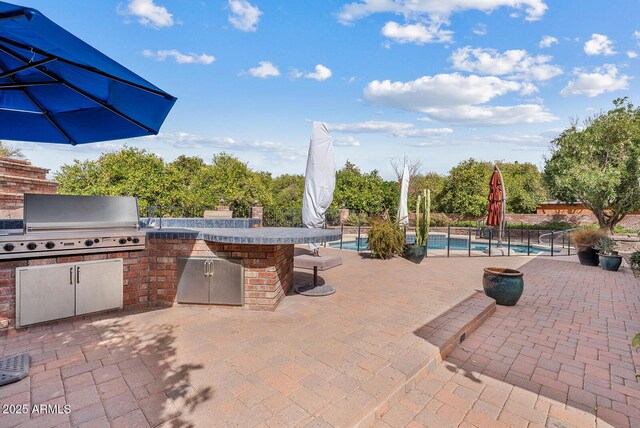 view of patio featuring a grill, fence, a fenced in pool, and area for grilling