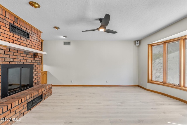 unfurnished living room featuring baseboards, a fireplace, visible vents, and light wood-style floors