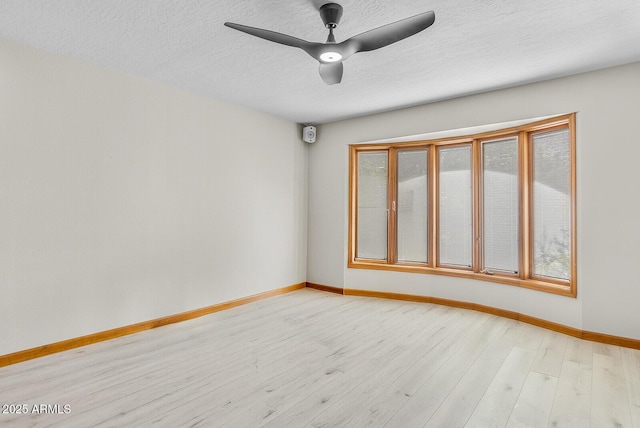 unfurnished room with ceiling fan, light wood-style flooring, baseboards, and a textured ceiling